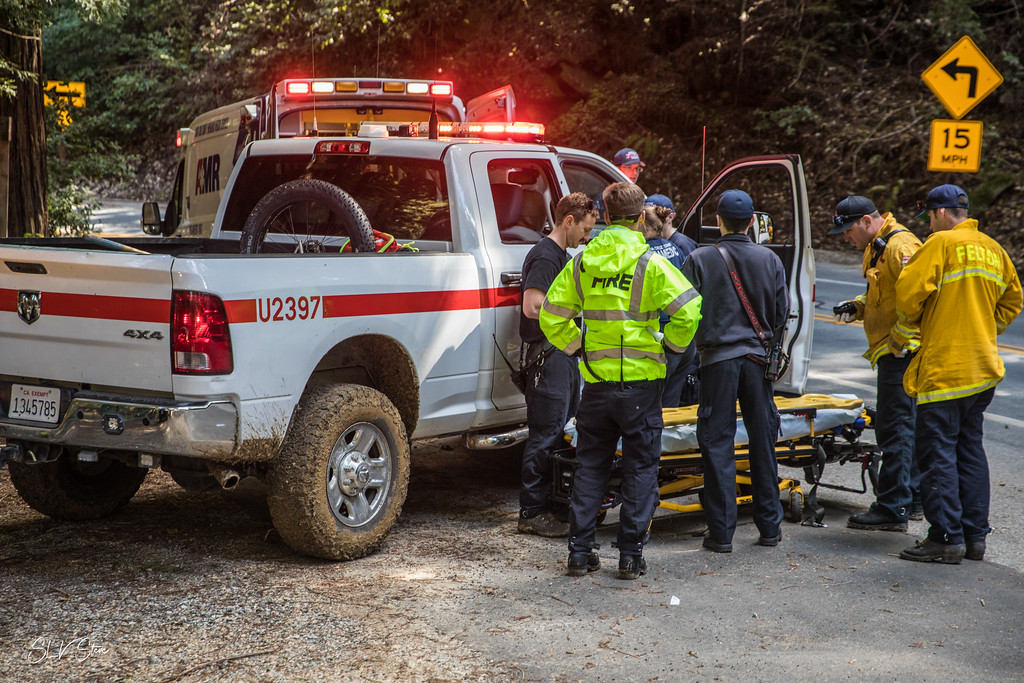 Firefighters standing near a truck and a patient transport gurney