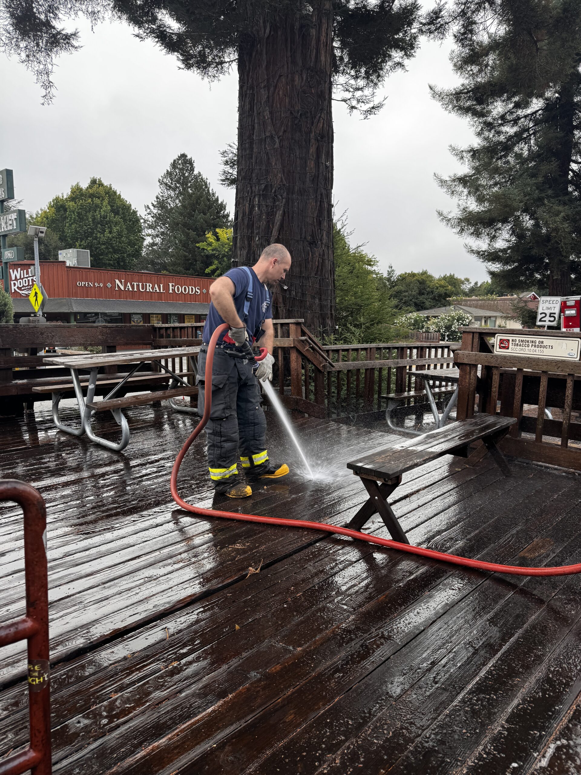 Felton firefighter washing down the redwood deck in downtown Felton