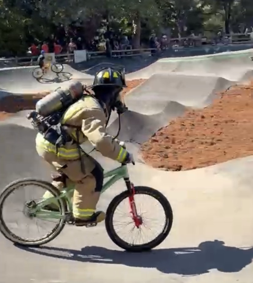 A Felton firefighter in full turnouts and air pack riding a bike on the new pump track